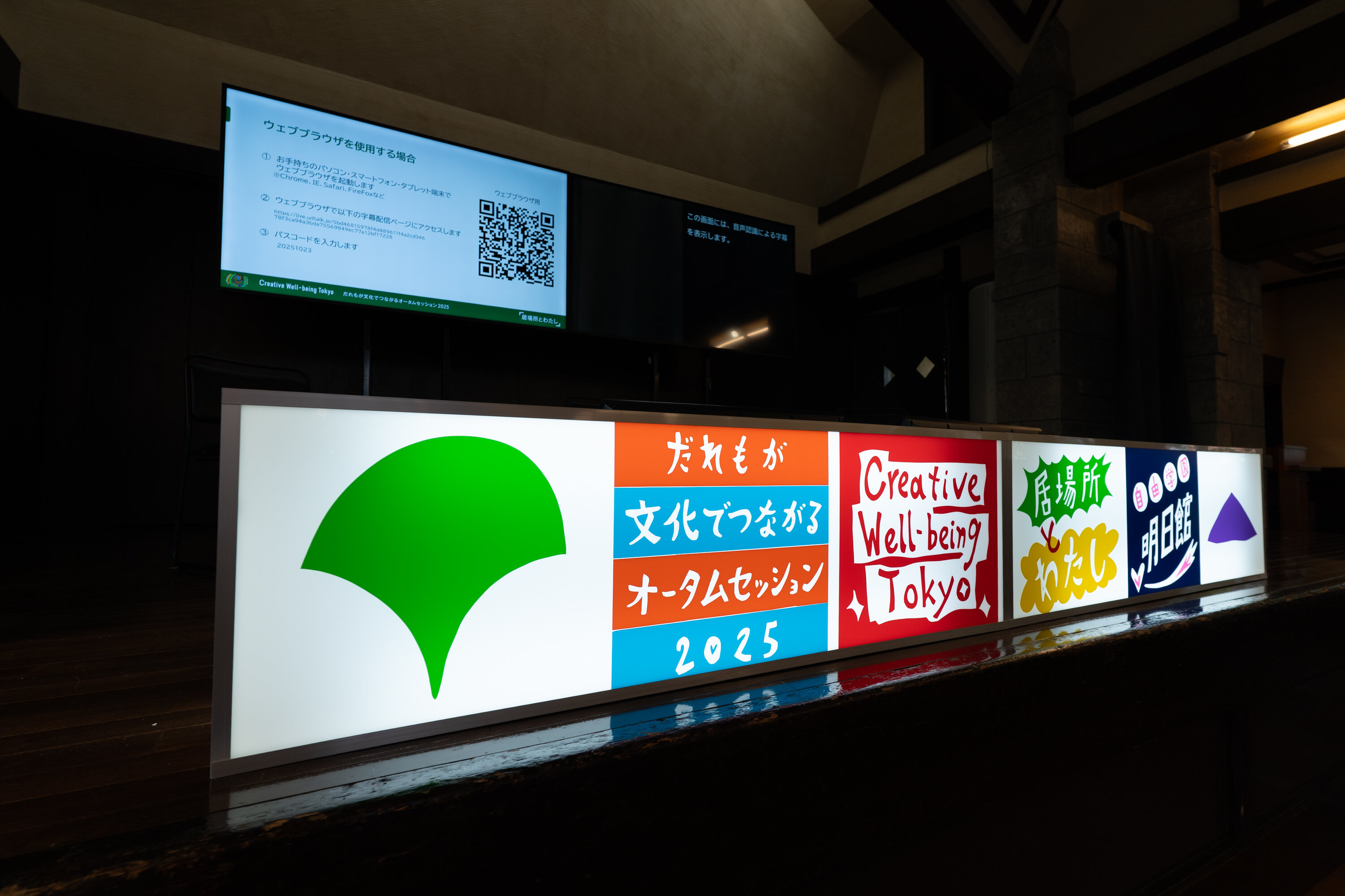 舞台上に横長の看板作品があり、ネオンの明かりのように発光している。